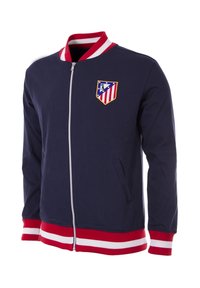 Marine blauwe ritsjack met een rood-wit gestreepte geribbelde kraag en manchetten. Heeft een geborduurd teamlogo op de linkerborst en twee zijzakken.