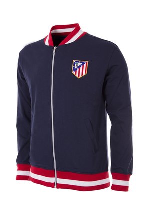 Marine blauwe ritsjack met een rood-wit gestreepte geribbelde kraag en manchetten. Heeft een geborduurd teamlogo op de linkerborst en twee zijzakken.