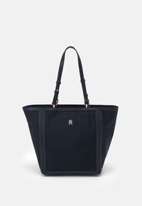 Borsa a spalla in nylon blu navy con due tracolle regolabili, hardware dorato con logo sul davanti e un design strutturato con cuciture laterali distintive.