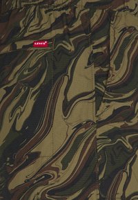 Shorts cargo Levi's dans un motif camouflage vert et marron. Tissu texturé avec une taille élastique et une poche latérale.