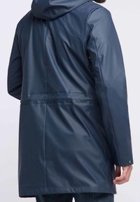 Marinblå vattentät parka med huva, slät yta, knälång, justerbart dragsnöre i midjan och knappstängning vid ärmsluten.