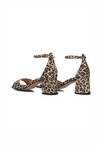 Sandales à talons hauts en imprimé léopard avec bout ouvert, talon épais, bride de cheville et texture lisse. Couleur : beige avec taches noires.