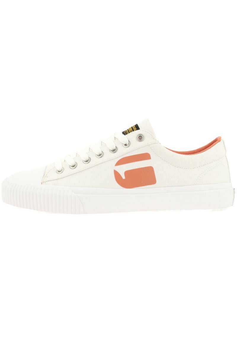 Baskets en toile couleur écru avec une semelle en caoutchouc texturé, arborant un logo orange contrastant et un collier de cheville rembourré.