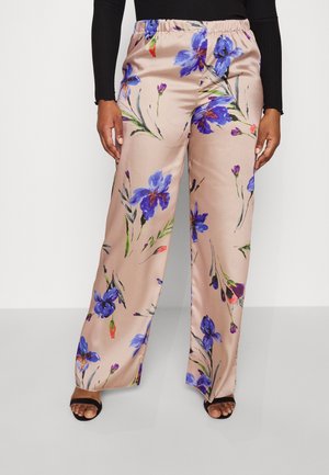 Beige bukser med vide ben med blå og lilla blomstret print, båret med sort top med lange ærmer og sorte åbne hæle.