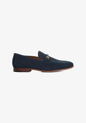 Navy suede loafers with a stitched toe design and a decorative hardware accent. Brown rubber sole. Upper features a smooth, matte texture.