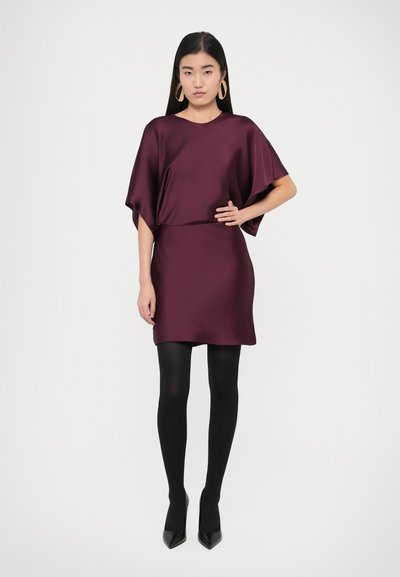 Rochie din satin burgundy cu mâneci largi, talie mulată și lungime deasupra genunchiului. Purtați cu ciorapi negri și pantofi negri cu toc ascuțit.