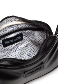 Schwarze Lederhandtasche mit einem Reißverschluss. Das Innenfutter hat ein gemustertes Design in Beige und Blau und zeigt das Markenlabel "Pikolinos."