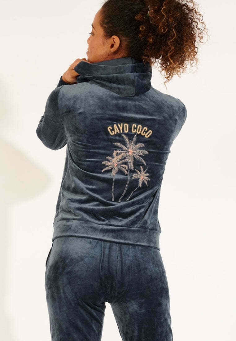 Tuta in velluto blu scuro con colletto alto, caratterizzata da ricami "CAYO COCO" e palme sulla schiena. Tessuto liscio, design aderente.
