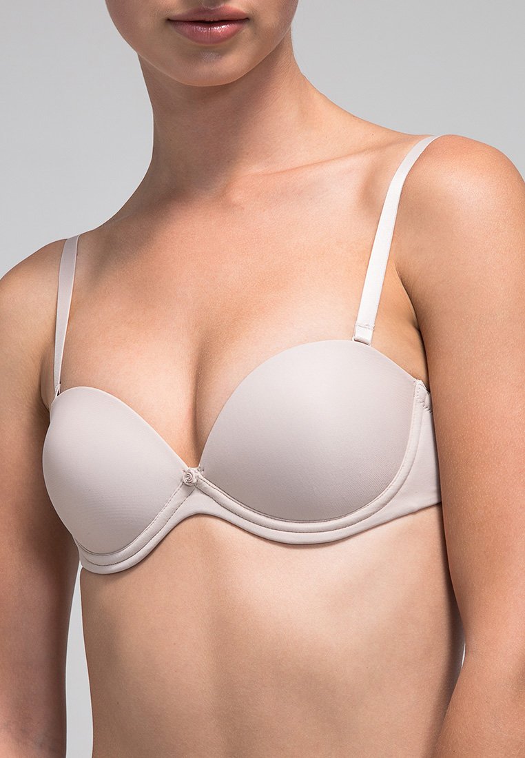 Sostén acolchado beige con aros, tirantes delgados ajustables y una textura suave. Presenta un detalle de lazo en el centro y copas sin costuras.