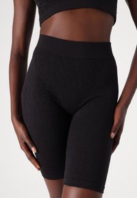 Zwarte high-waisted shorts met een textuurpatroon, een nauwsluitend ontwerp en naadloze randen, gemaakt van een rekbare, ademende stof.