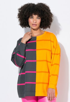 Chemise à manches longues avec un design divisé, présentant des sections orange et gris foncé, accentuée par des rayures horizontales roses, fabriquée en tissu léger.