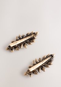 Antike Haarklammern in Silberoptik, geformt wie Blätter, mit einer strukturierten Oberfläche und einem Metallverschluss, auf hellem Hintergrund präsentiert.