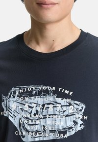 Marineblå kortærmet t-shirt med et grafik af en lys blå vintage bil og hvid tekstoverlejring. Rund hals-design med en glat tekstur.