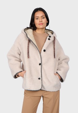 Veste à capuche en fausse fourrure blanche avec des boutons noirs, bordure grise contrastante et cordons de serrage à motif léopard. Conçue avec des poches latérales.