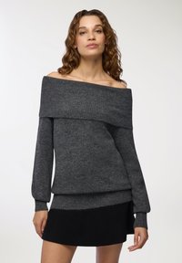 Sweter z odkrytymi ramionami w ciemnoszarym kolorze z prążkowanym dekoltem i mankietami. Miękka faktura, warstwowy design oraz wydłużone rękawy z delikatnym rozkloszowaniem.