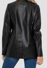 Blazer en cuir noir avec une texture lisse, ajustement sur mesure et silhouette droite. Comprend des manches longues et un détail de couture au centre au dos.