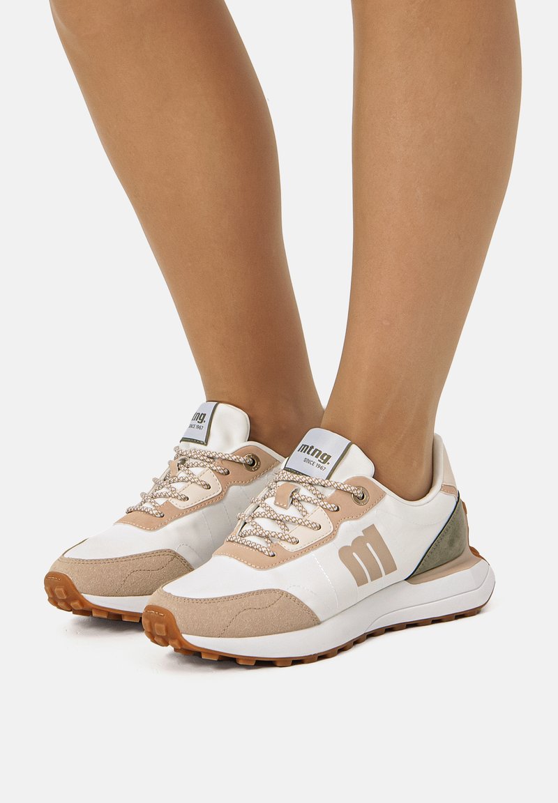 Baskets blanches et beiges avec des accents en daim texturé, des lacets plats et une languette à logo. Semelles en caoutchouc avec une accroche à motif.