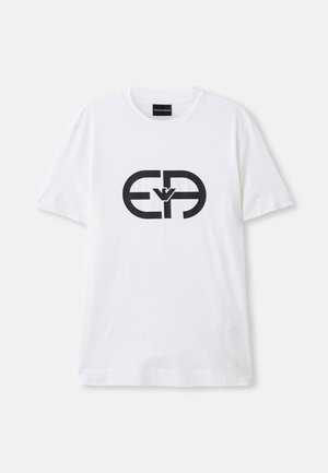 T-shirt en coton blanc avec un grand logo graphique noir au centre. Manches courtes et col rond. Design simple, texture douce.