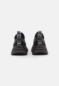 Schwarze sportive Sneakers mit einem strukturierten Obermaterial, einer dicken Sohle und kontrastierenden weißen Logos auf den Zuglaschen der Ferse.