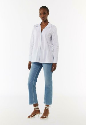  Lichtblauw gestreept overhemd met knopen en een kraag, gecombineerd met lichtdenim cropped jeans en witte strappy haksandalen.