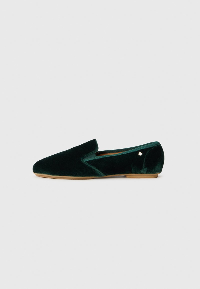 Mocassin en velours vert avec un bout pointu, doté d'un panneau latéral en élastique et d'un petit logo métallique sur le talon.