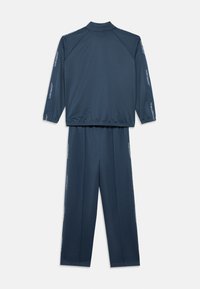 Ναυτικό μπλε σετ φόρμας δύο τεμαχίων με μακριά μανίκια, ελαστικές μανσέτες και το κείμενο «Jordan» που τρέχει κατά μήκος των μανικιών και των ποδιών του παντελονιού.