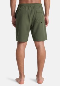 Πράσινα μαγιό με ελαστική μέση, πίσω τσέπη και λεία υφή. Ο σχεδιασμός διαθέτει μινιμαλιστικές λεπτομέρειες και δεν έχει εμφανή μοτίβα.