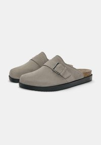 Zoccoli in suede grigio con suola in gomma nera, ampia fascia con fibbia in argento e soletta in sughero per il massimo comfort. Texture liscia in tutto il prodotto.