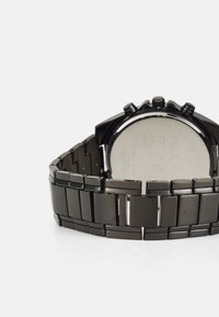 Montre en acier inoxydable noir avec un bracelet à maillons. Fini lisse et brillant avec un boîtier rond et trois boutons de fonction.