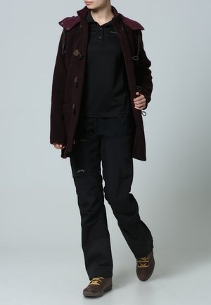 Abrigo de lana burdeos con toggles, camiseta de polo negra, pantalones negros y botas de senderismo marrones. Diseño funcional con bolsillos y características ajustables.