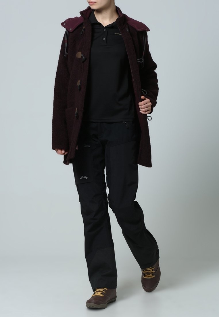 Burgunderröd ullkappa med snörningar, svart polotröja, svarta byxor och bruna vandringsskor. Funktionell design med fickor och justerbara egenskaper.