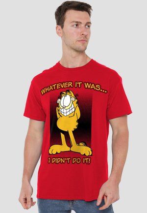Red cotton t-shirt featuring a graphic of a cartoon cat and text: "WHATEVER IT WAS... I DIDN'T DO IT!" Bold typography and playful design.