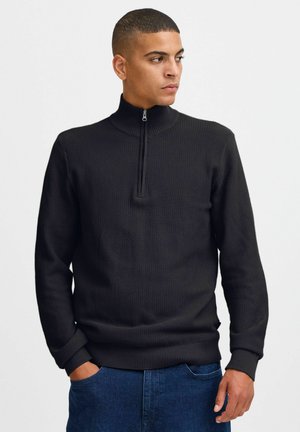 Zwarte gebreide pullover met een hoge kraag en een halve rits, voorzien van een gemêleerd patroon en geribbelde manchetten. Casual stijl geschikt voor het layers.