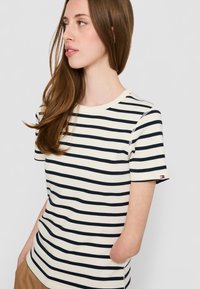 Striped t-skjorte med korte ermer i krem og marineblå, med ribbet halslinning og logodetalj på ermet. Laget av bomull, med en glatt tekstur.