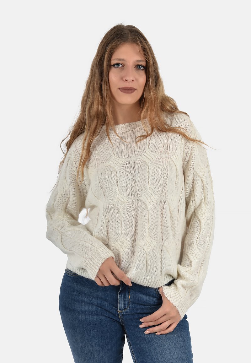 Maglione a maglia color crema con un motivo a onda testurizzato, vestibilità morbida e polsini a costine, abbinato a jeans in denim blu.