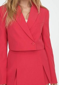 Blazer rosa recortado con cierre de un solo botón, solapas afiladas y bolsillo parche. Tela suave con ajuste entallado y diseño estructurado.