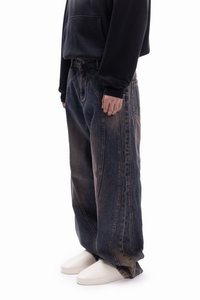Baggy dark blue denim jeans with faded accents, featuring a loose fit and side seams. Worn with a black hoodie and white shoes.