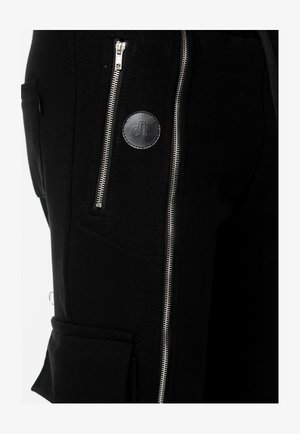 Czarne spodnie wykonane z mieszanki bawełny, z zamkiem błyskawicznym w kieszeni, detalem logo i gładką teksturą. Szew boczny z akcentem w postaci srebrnego zamka.