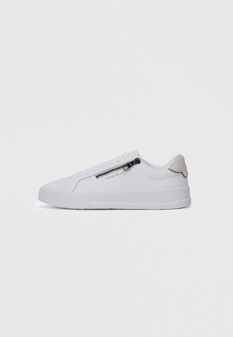 Hvit lav sneaker med siderom zipp og snøring, beige hæltab, og "Tommy Hilfiger" logo på siden.