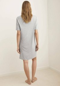 Grå kjole med korte ærmer lavet af blødt stof, knælang med løs pasform. Bagsiden har et enkelt design uden udsmykninger.