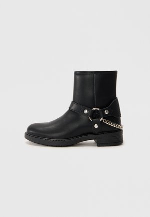 Black leather ankle boots with a rounded toe, featuring a textured back panel, adjustable strap, and chain detail on the side.