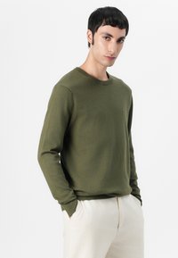 Olivengroene crew neck sweatshirt van een zachte stof met lange mouwen, met ribgebreide manchetten en een klein logo-accent op de borst.