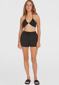 Crni bikini top s trokutastim čašama, uparen s crnim kupaćim šortsevima na vezanje. Glatka tekstura, jednostavan dizajn i podesive naramenice.