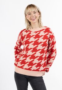 Svetr s kostkovaným vzorem v červené a růžové barvě, pletený materiál, kulatý výstřih, ribbed lem, volný střih, dlouhé rukávy a minimalistické designové prvky.