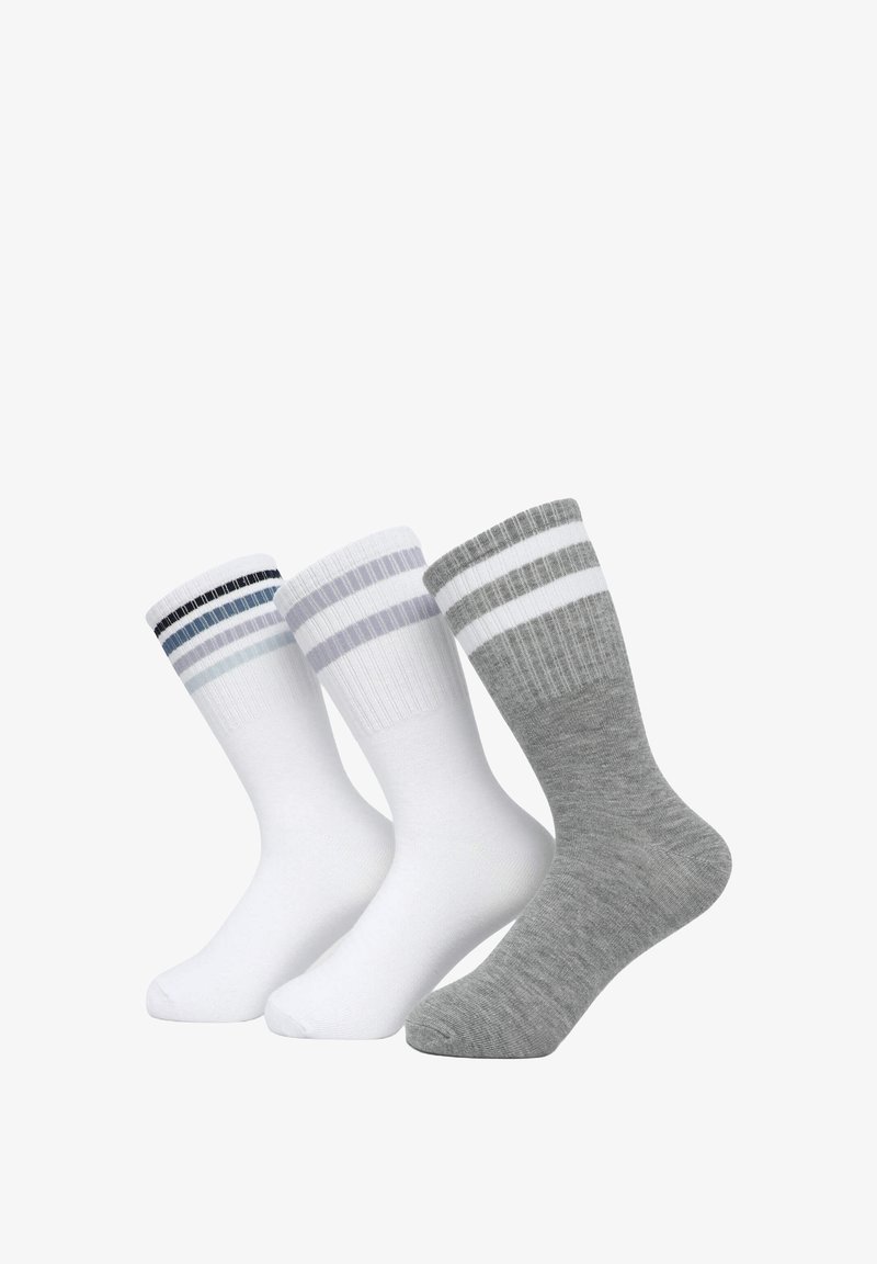 Trzy pary skarpetek: dwie białe z kolorowymi paskami i jedna szara z białymi paskami. Mieszanka bawełny, prążkowana faktura, długość do połowy łydki.
