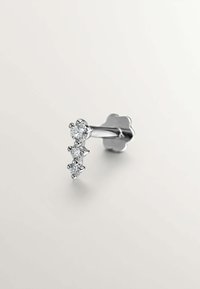 Pendiente de plata con tres piedras redondas transparentes dispuestas verticalmente, con un respaldo en forma de flor. Superficie metálica lisa, diseño minimalista.