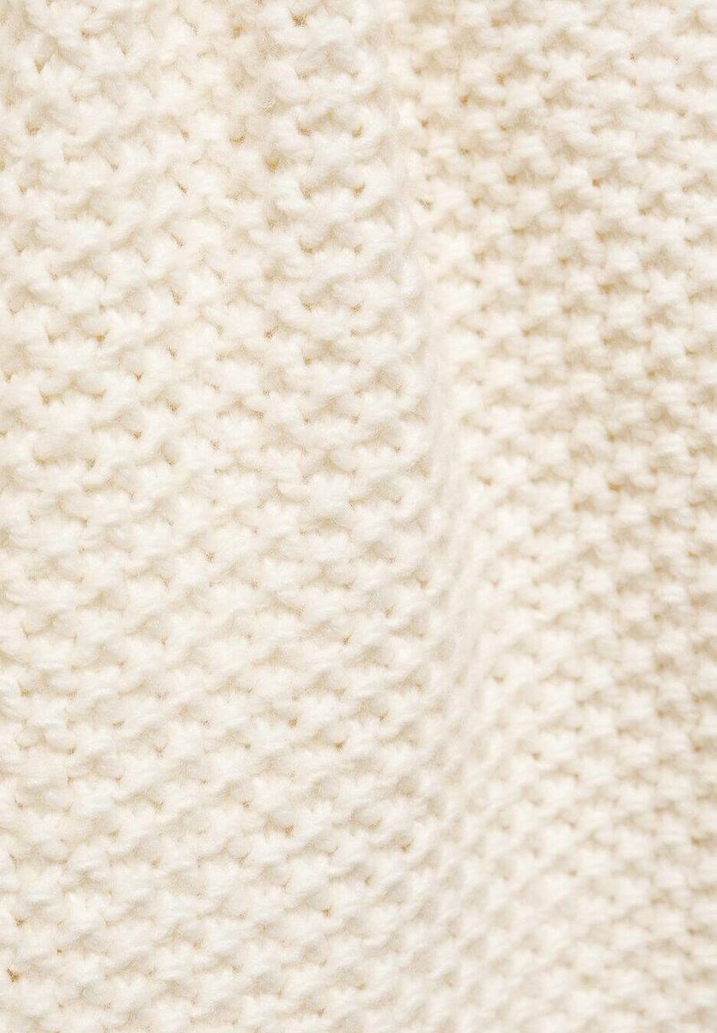 Tissu tricoté en blanc cassé avec un motif texturé, présentant une apparence douce et duveteuse, avec un design tissé créant un aspect chaleureux.