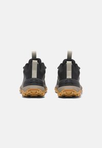 Zapatos de senderismo negros con una parte superior de textil duradera, suela de tracción de goma y un acento gris. Asa en la parte trasera para facilitar el uso.