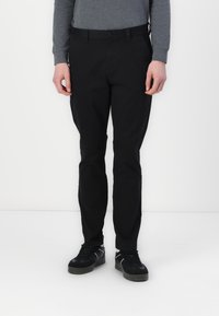 Čierne nohavice z hladkého materiálu, so slim fit strihom, pútkami na opasok, prednými vreckami a jedným gombíkom na zapínanie.