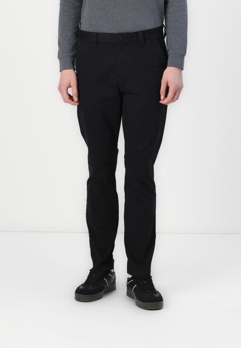 Čierne nohavice z hladkého materiálu, so slim fit strihom, pútkami na opasok, prednými vreckami a jedným gombíkom na zapínanie.